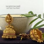 Lakshmi Grace Kemp Jhumka crafted from premium brass with a matte gold polish, featuring a Goddess Lakshmi motif, clustered pearls, and traditional Kemp temple design for women.