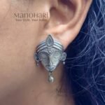 Ziya Silver Elegance Studs featuring an intricately carved divine face motif with an oxidised silver-tone finish and heritage-inspired craftsmanship