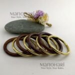 **The Vanya Rustic Wood Bangles Set showcases the timeless beauty of handcrafted wooden jewellery with a warm rustic brown finish accented by elegant gold-tone detailing. This set of **8 lightweight wooden bangles** is thoughtfully designed to offer both comfort and style, featuring an **inner diameter of approximately 6 cm** for a comfortable fit. Perfect for stacking or wearing individually, these versatile bangles effortlessly complement **Kerala Kasavu sarees, cotton sarees, silk sarees, kurtis, dresses, and Indo-western outfits**. Ideal for **Onam, weddings, festivals, office wear, casual outings, cultural celebrations, and everyday styling**, the **Vanya Rustic Wood Bangles Set** adds a touch of natural elegance to every look. Exclusively curated by **Manohari Style**, this beautifully crafted bangle set blends rustic charm, modern versatility, and timeless craftsmanship, making it a must-have accessory for every woman's jewellery collection.**