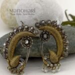 **Mayurika Peacock Pearl Ear Cuff crafted from premium brass with an elegant two-tone finish, featuring an intricate peacock design adorned with shimmering stones and delicate pearl accents for a regal traditional look.**