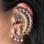 **Mayurika Peacock Pearl Ear Cuff crafted from premium brass with an elegant two-tone finish, featuring an intricate peacock design adorned with shimmering stones and delicate pearl accents for a regal traditional look.**