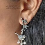 Celebrate the beauty of nature with the **Avira Bird Leaf Earrings**, expertly crafted from **pure brass** with an elegant **silver replica finish** and adorned with delicate **glass pearl beads**. Measuring approximately **4.5 cm**, these lightweight statement earrings feature a graceful bird and leaf-inspired design that blends traditional artistry with contemporary style. Perfect for **everyday wear, office, festivals, weddings, Onam, and special occasions**, they pair beautifully with sarees, kurtis, dresses, and Indo-western outfits, making them a timeless addition to every woman's jewellery collection.