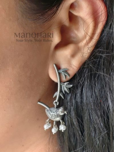 Celebrate the beauty of nature with the **Avira Bird Leaf Earrings**, expertly crafted from **pure brass** with an elegant **silver replica finish** and adorned with delicate **glass pearl beads**. Measuring approximately **4.5 cm**, these lightweight statement earrings feature a graceful bird and leaf-inspired design that blends traditional artistry with contemporary style. Perfect for **everyday wear, office, festivals, weddings, Onam, and special occasions**, they pair beautifully with sarees, kurtis, dresses, and Indo-western outfits, making them a timeless addition to every woman's jewellery collection.