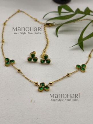 **Juwana Floral Heritage Necklace Set crafted from premium gold-plated metal, featuring radiant emerald green floral daisy motifs, a delicate gold link chain, and matching floral earrings for women.**