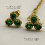 **Juwana Floral Heritage Necklace Set crafted from premium gold-plated metal, featuring radiant emerald green floral daisy motifs, a delicate gold link chain, and matching floral earrings for women.**