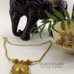 **Aditi Pearl Temple Pendant Set crafted from premium brass and copper metal with a luxurious Matte Gold Polish finish, featuring a 3 cm temple-inspired pendant, matching 3 cm jhumka earrings, clustered pearls, and artificial stones for women.**