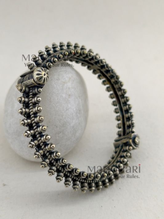 MN-BG-SLV-AVS-01_1 **Aaranya Vintage Silver Bangle crafted from premium brass with a refined silver-plated finish, featuring a vintage-inspired openable design and a comfortable 5.5 cm inner diameter for timeless ethnic elegance.**