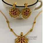 **The Meher Antique Kemp Necklace Set is a timeless celebration of South Indian heritage, crafted from **premium brass** with a luxurious **matte gold-plated finish**. Embellished with vibrant **traditional Kemp stones**, this elegant necklace showcases intricate temple-inspired craftsmanship that radiates regal charm. The **21 cm necklace** features an **adjustable extension chain** for a comfortable fit, while the matching **4.5 cm earrings** complete the coordinated look. Perfectly paired with **Kerala Kasavu sarees, Kanchipuram silk sarees, lehengas, Anarkalis, and other traditional attire**, this exquisite jewellery set is ideal for **Onam, weddings, temple visits, engagements, receptions, festivals, and bridal celebrations**. Exclusively curated by **Manohari Style**, the **Meher Antique Kemp Necklace Set** combines heritage artistry, premium craftsmanship, and timeless elegance, making it a treasured addition to every woman's ethnic jewellery collection.**