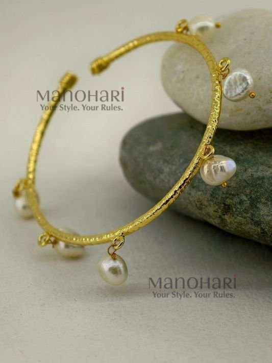 MN-BR-PRL-KGE-01_1 Kiara Gold Pearl Elegance Bangle crafted from brass, featuring an adjustable pearl hanging design and approximately 6 cm inner diameter.
