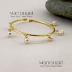 Kiara Gold Pearl Elegance Bangle crafted from brass, featuring an adjustable pearl hanging design and approximately 6 cm inner diameter.